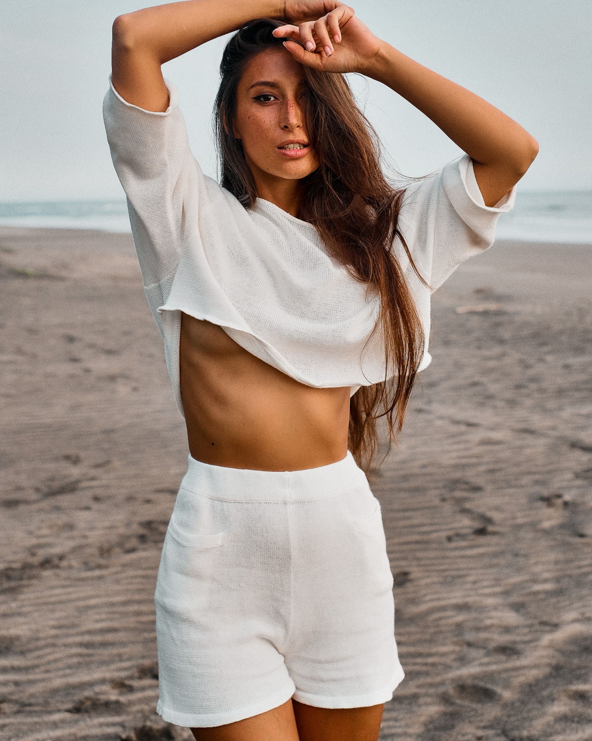 Woman in white outfit standing at the beach