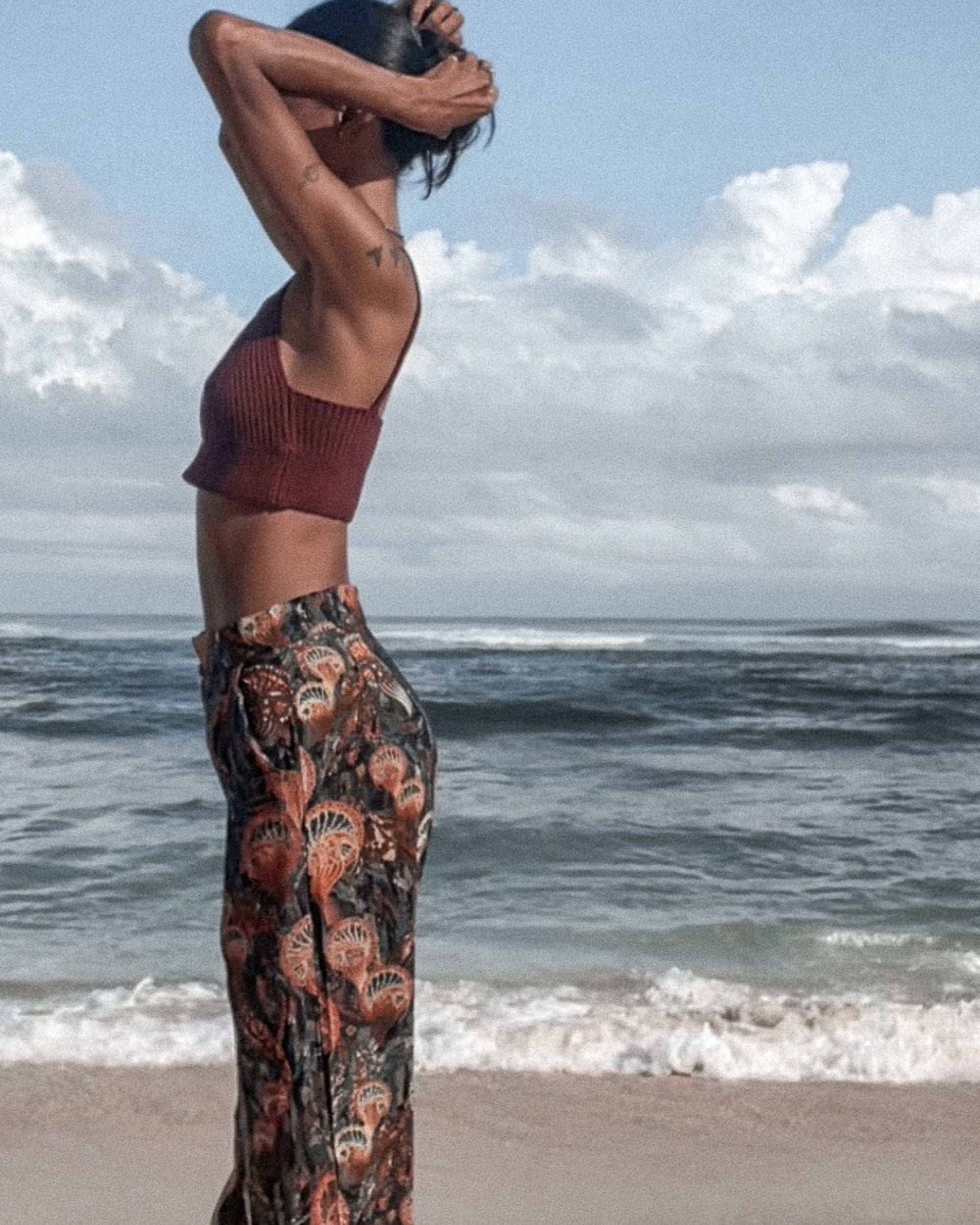 Person standing on a beach with ocean waves and cloudy sky in the background