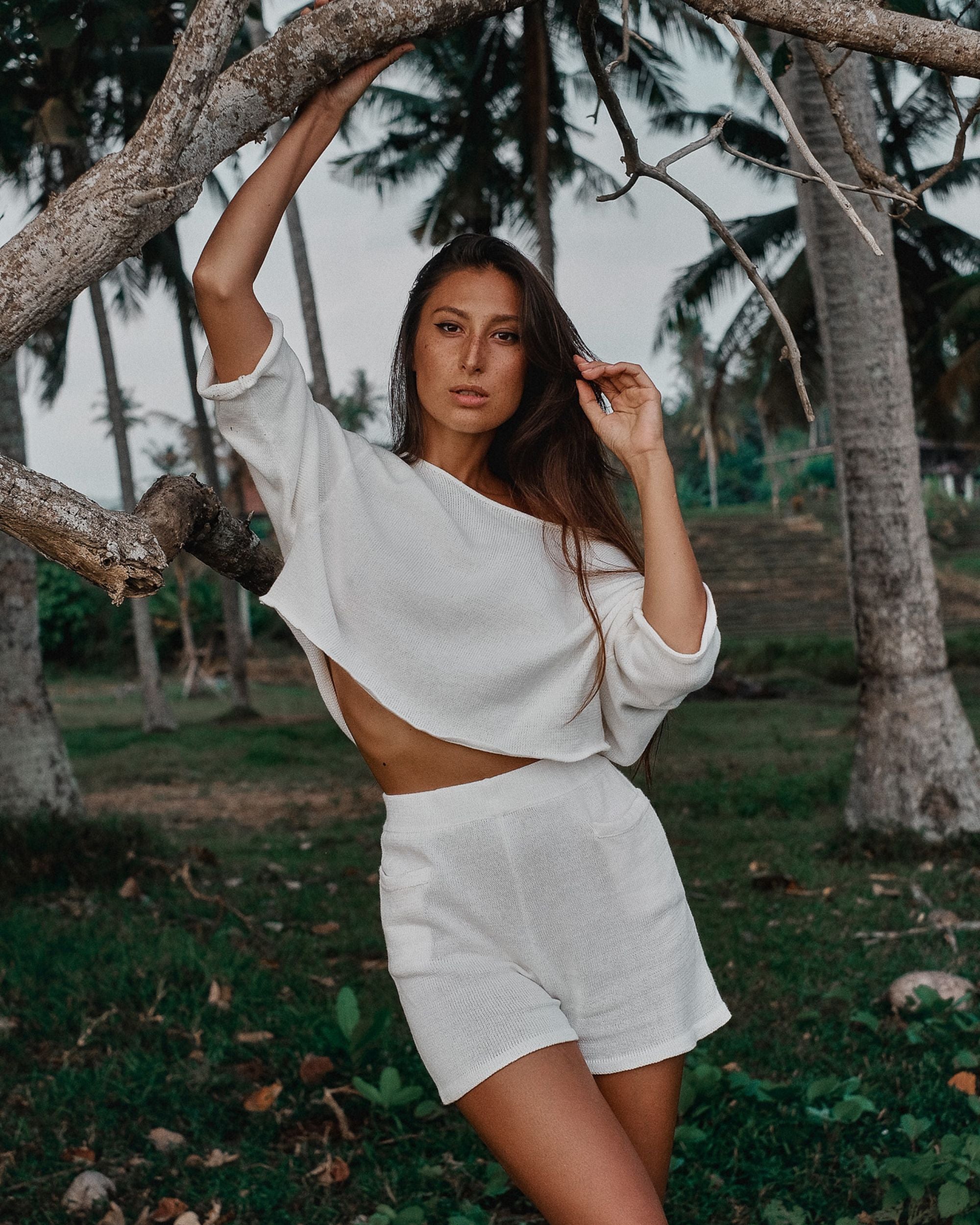 Woman in white outfit standing under a tree
