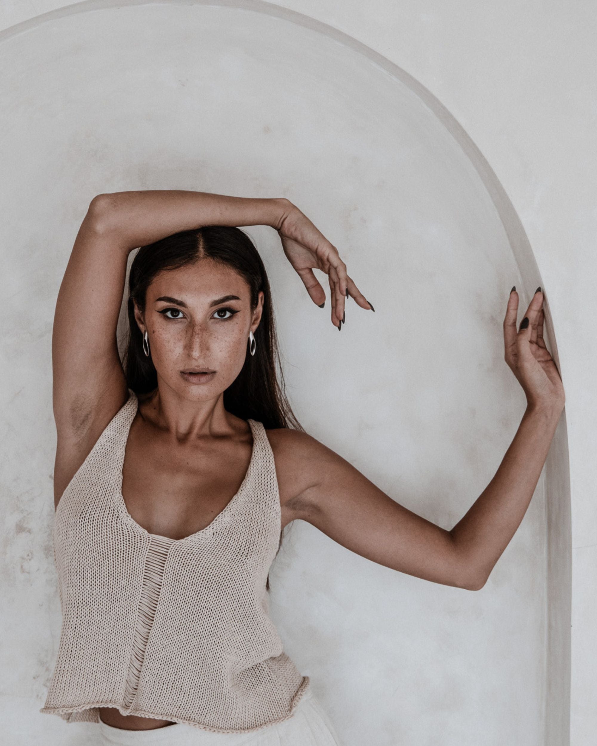 Woman wearing a beige knitted top against a white background